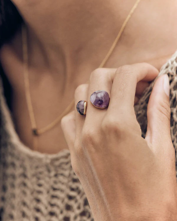 Anello PDPAOLA Amethyst Gravity AN01-D41-16 indossato al dito, con due ametiste asimmetriche e design aperto.