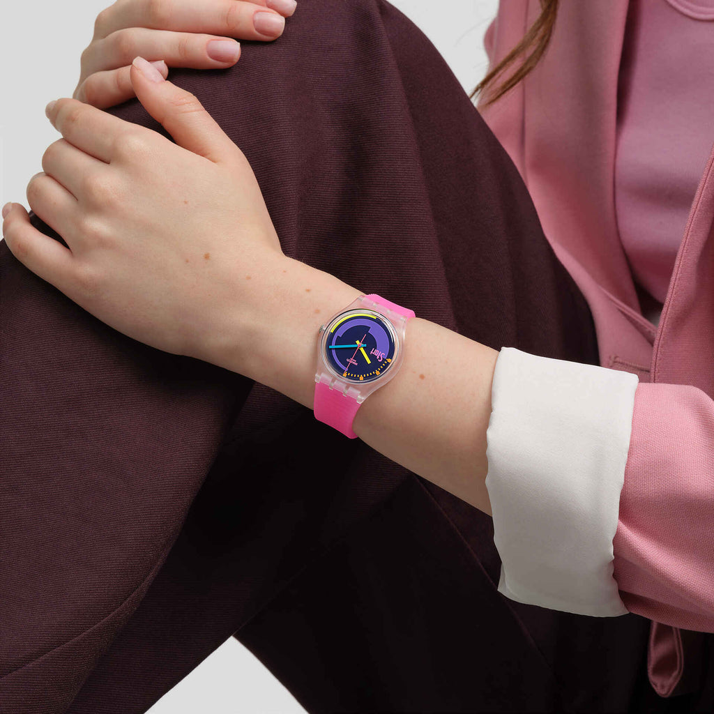 Swatch Neon Pink Podium SO28K111 indossato al polso con giacca rosa e polsino bianco, cinturino rosa e quadrante a contrasto.