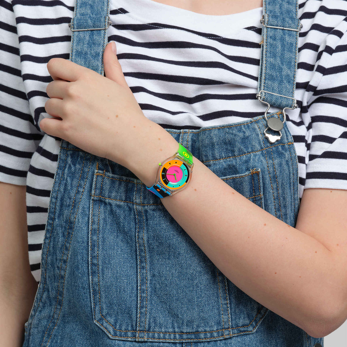 Swatch NEON HOT RACER SS08K119 indossato al polso con salopette in denim e maglia a righe, CICCO Gioielleria.