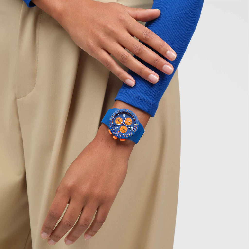 Swatch PRIMARILY BLUE SUSN419 indossato al polso, cronografo blu e arancione abbinato a un look casual.