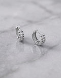 Orecchini a cerchio OR0104 in argento 925 con zirconi rettangolari e rotondi e chiusura a scatto su sfondo grigio, CICCO Gioielleria.