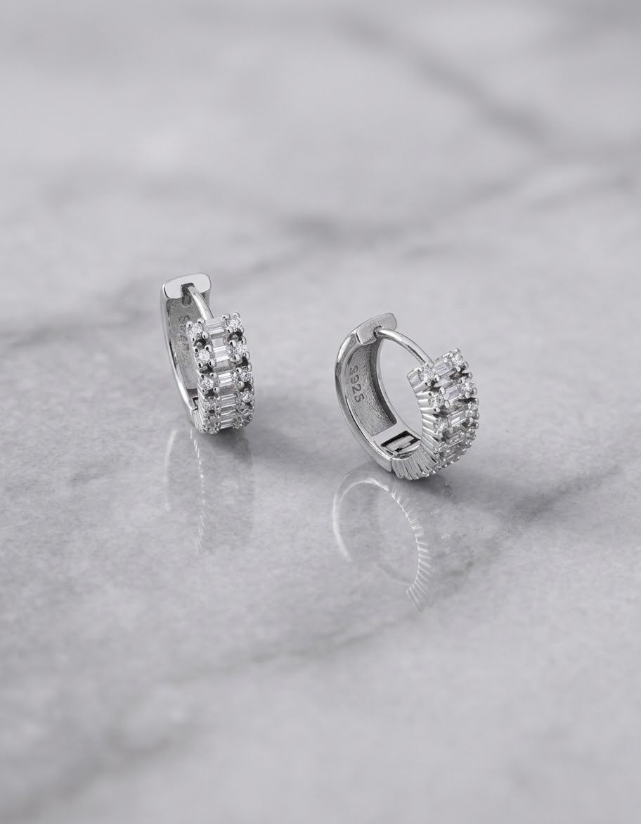 Orecchini a cerchio OR0104 in argento 925 con zirconi rettangolari e rotondi e chiusura a scatto su sfondo grigio, CICCO Gioielleria.