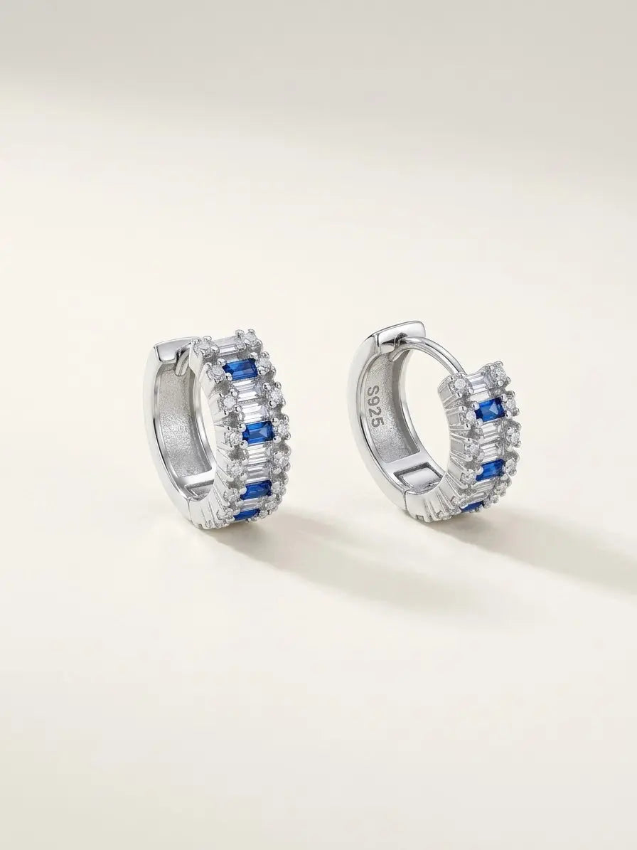 Orecchini a cerchio OR0157 in argento 925 con zirconi blu, pietre bianche e chiusura a scatto, su sfondo chiaro. CICCO Gioielleria.