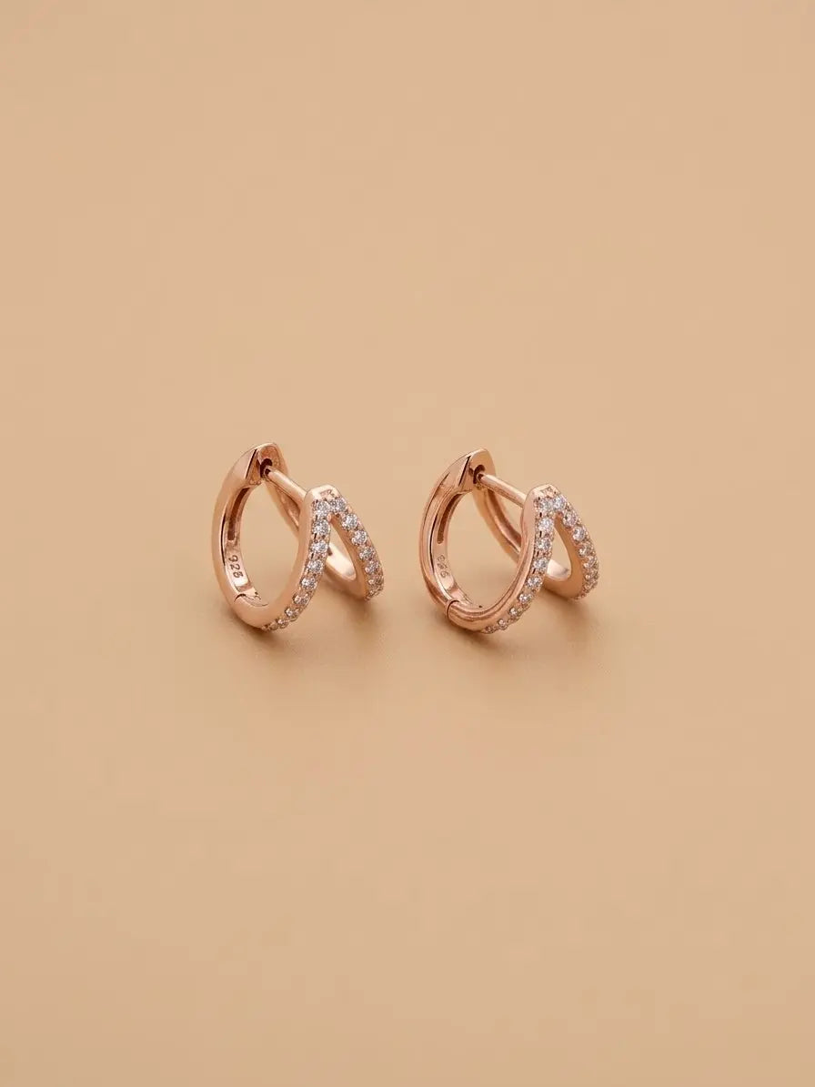 Orecchini a V OR0132 in argento 925 rosé con punti luce bianchi su sfondo beige, CICCO Gioielleria.