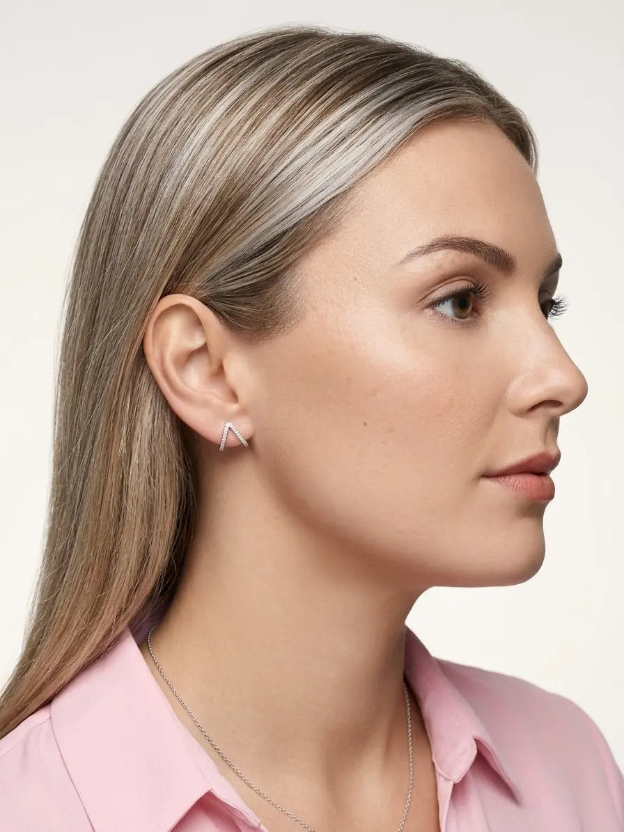 Orecchino a V OR0132 rosé con profilo luminoso indossato, con capelli dietro l’orecchio.