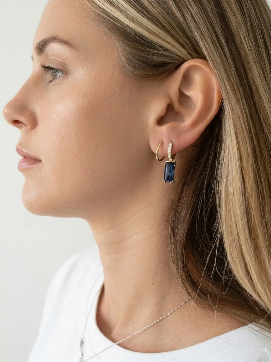 Monorecchino CICCO925 OR0150 in argento 925 dorato con lapis blu a baguette, indossato al lobo da una modella di profilo, CICCO Gioielleria.