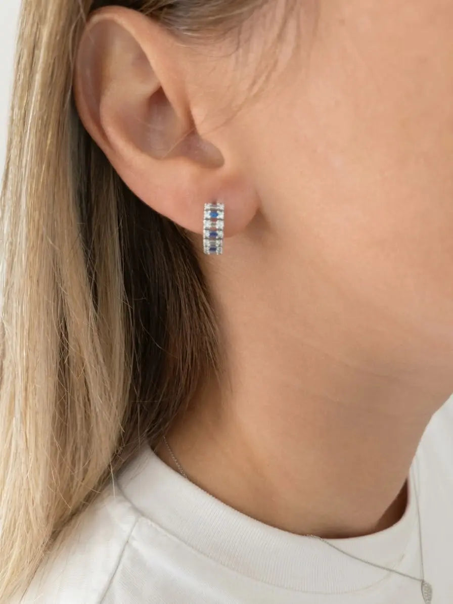 Orecchino a cerchio OR0157 in argento 925 con zirconi blu e pietre bianche indossato, con capelli dietro l’orecchio. CICCO Gioielleria.