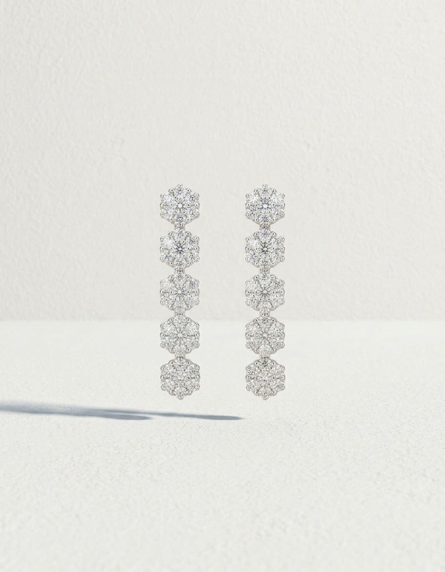 Orecchini pendenti OR0106 in argento 925 con cinque fiori di zirconi bianchi in sequenza su sfondo chiaro, CICCO Gioielleria.