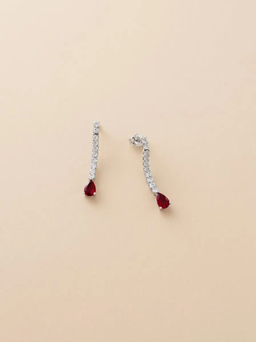 Orecchini pendenti in argento 925 con fila di zirconi e pietra rossa a goccia su fondo neutro, CICCO Gioielleria.