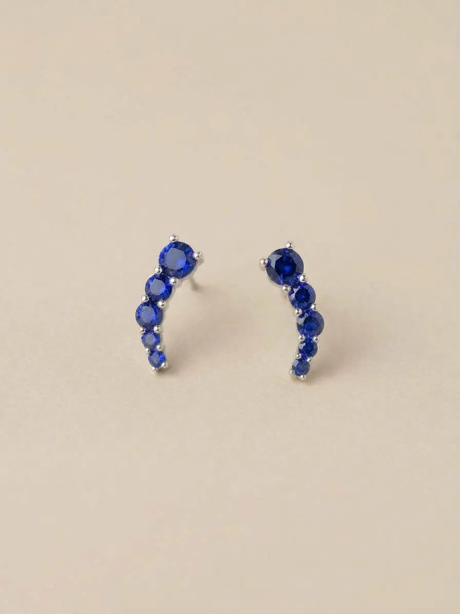 Orecchini a virgola OR0172 in argento 925 con pietre blu rotonde a scalare su fondo chiaro, CICCO Gioielleria.