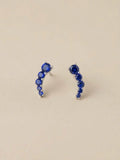 Orecchini a virgola OR0172 in argento 925 con pietre blu rotonde a scalare su fondo chiaro, CICCO Gioielleria.